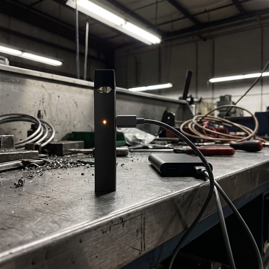 A disposable vape device on a factory charging cable before shipping