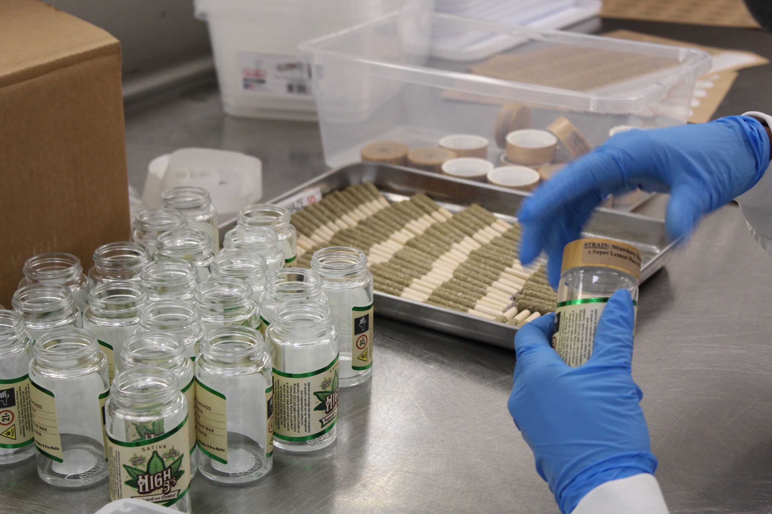 A labeled High 5's jar being packed next to a tray of finished pre-rolls