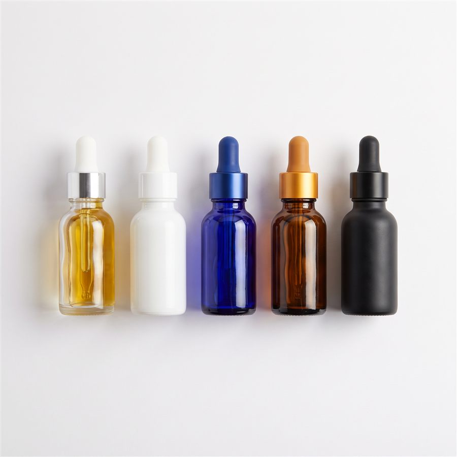 Five tincture dropper bottles side by side in clear, white, blue, amber, and black glass